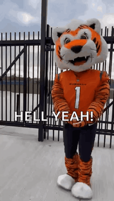 A Mascot Dressed As A Tiger Is Standing In Front Of A Fence And Says `` Hell Yeah '' . GIF