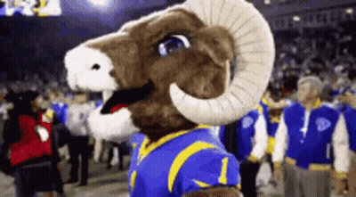 A Mascot For The Los Angeles Rams Is Standing On A Football Field GIF