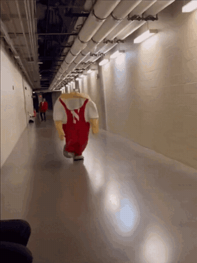 A Mascot From The University Of Iowa Is Running Down A Hallway GIF
