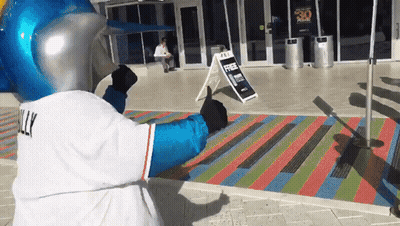 A Mascot Giving A Thumbs Up In Front Of A Sign That Says Free Parking GIF