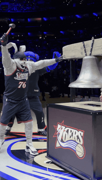 a mascot holding a hammer in front of a sign that says 76ers