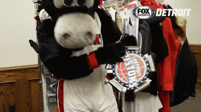 A Mascot In A Detroit Pistons Uniform Holds A Trophy GIF