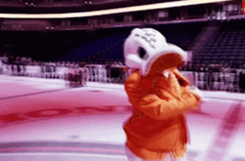 A Mascot In A Duck Costume Is Standing On A Hockey Rink . GIF