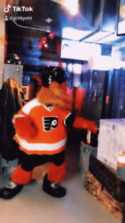 a mascot in a flyers jersey is dancing in a room