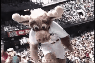 A Mascot In A Moose Costume Is Jumping In The Air In Front Of A Crowd . GIF