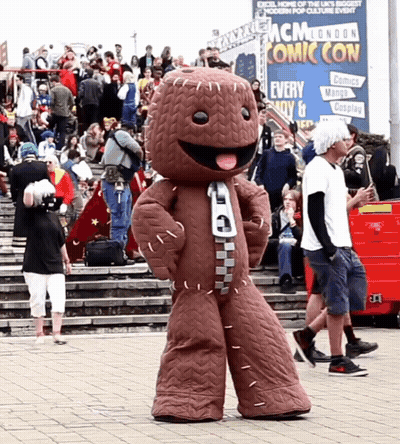 A Mascot In Front Of A Mcm London Comic Con Sign GIF