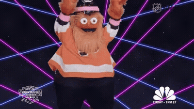 A Mascot Is Dancing In Front Of A Glowing Background That Says Nbc GIF