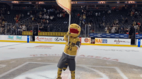 A Mascot Is Holding A Flag In Front Of A Sign That Says Las Vegas On It GIF