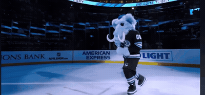 A Mascot Is On The Ice In Front Of An American Express Banner GIF