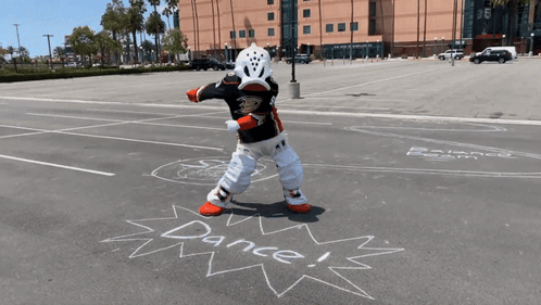 A Mascot Is Standing In A Parking Lot With The Words Dance Written In Chalk GIF