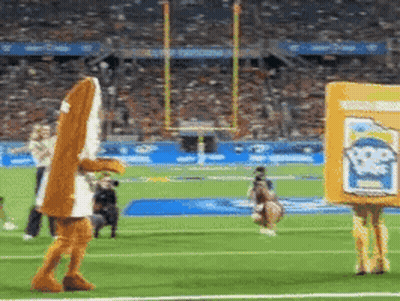 A Mascot Is Walking On A Football Field While Holding A Box That Says Popeye 'S GIF