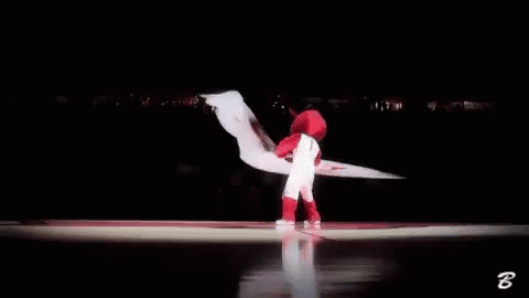 A Mascot Is Waving A Red And White Flag In A Basketball Court . GIF