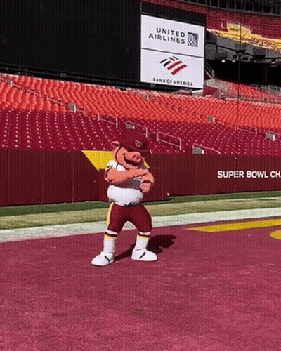 A Mascot Stands On A Football Field In Front Of A United Airlines Sign GIF