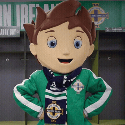 A Mascot Wearing A Green Jacket And A Blue Scarf With Northern Ireland On It GIF
