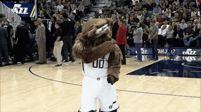 A Mascot Wearing A Number 00 Jersey Is Hugging Another Mascot On A Basketball Court GIF