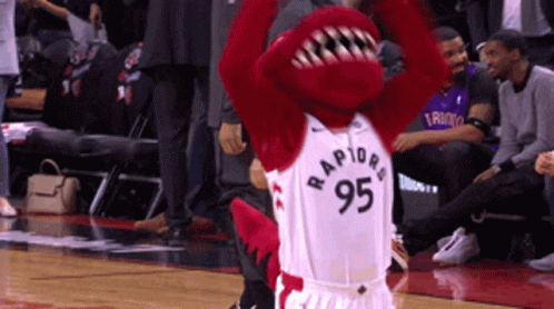 A Mascot Wearing A Raptors 95 Jersey Stands On A Basketball Court GIF