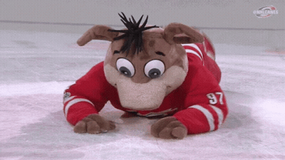 A Mascot Wearing A Red And White Jersey With The Number 97 On It Is Laying On The Ice . GIF