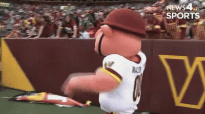 A Mascot Wearing A Redskins Jersey Is Dancing On A Field GIF