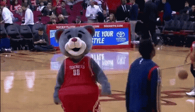 A Mascot Wearing A Rockets Jersey Is Standing On A Basketball Court . GIF