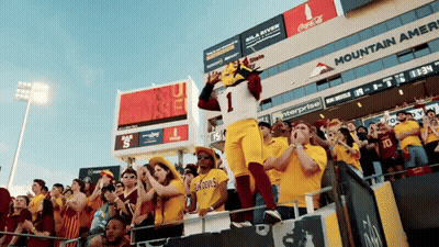A Mascot Wearing Number 1 Stands In Front Of A Crowd Of People GIF