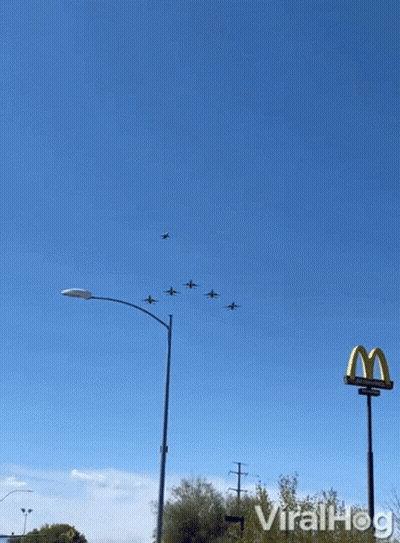 A Mcdonald 'S Sign Is In The Foreground Of A Group Of Planes In The Sky GIF