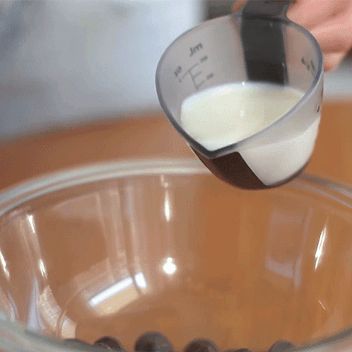 A Measuring Cup With The Letter E On It Is Being Poured Into A Glass Bowl GIF