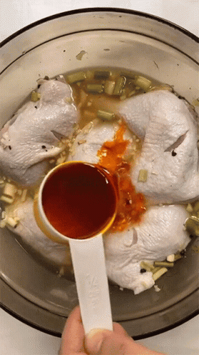 A Measuring Spoon Is Being Used To Pour Sauce Into A Bowl Of Chicken GIF
