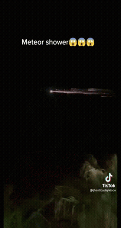 A Meteor Shower Is Visible In The Night Sky Over A Body Of Water . GIF