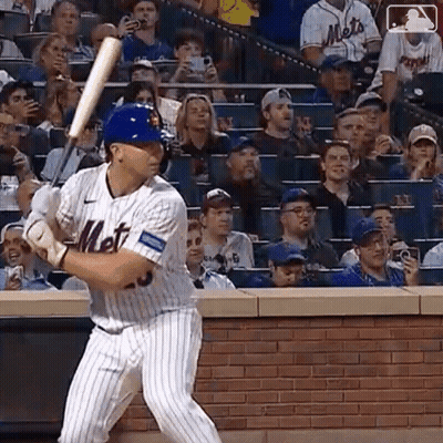 A Mets Baseball Player Is Swinging A Bat In Front Of A Crowd At A Baseball Game . GIF