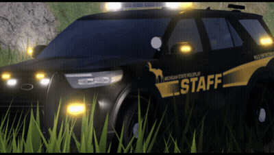 A Michigan State Police Car Is Parked In A Grassy Field GIF