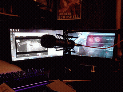 A Microphone Is Sitting In Front Of Two Computer Monitors And A Poster That Says American Bombshell GIF