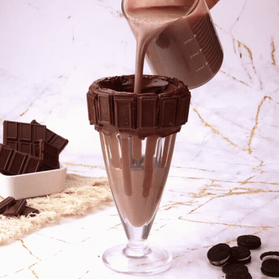 A Milkshake Is Being Poured Into A Glass With A Chocolate Decoration GIF