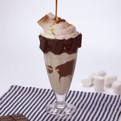 A Milkshake With A Chocolate Bar On Top And Whipped Cream GIF