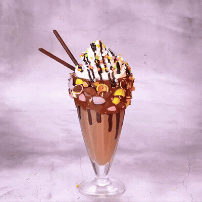 A Milkshake With M & M 'S And Oreos On Top Of It GIF