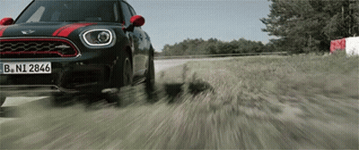 A Mini Cooper Driving Down A Dirt Road GIF