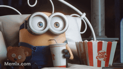 A Minion Is Sitting On A Bed With A Cup Of Soda And A Bucket Of Popcorn GIF