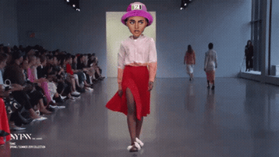 A Model Walks Down A Runway Wearing A Pink Hat And A Red Skirt GIF