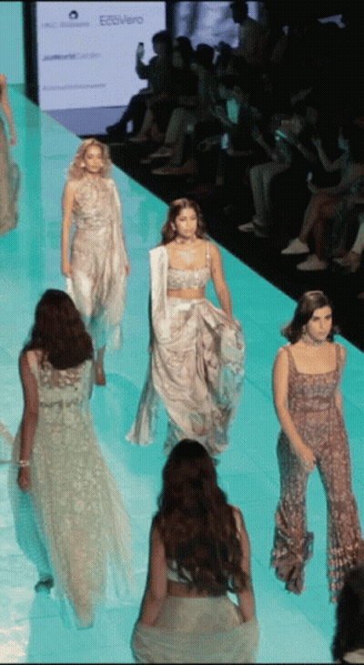 A Model Walks Down The Runway At A Fashion Show In Front Of A Sign That Says Ecovero GIF