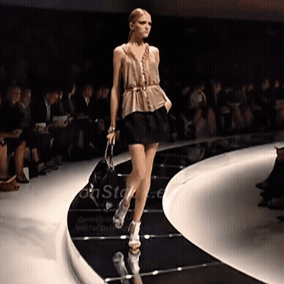 A Model Walks Down The Runway At A Fashion Show With A Sign That Says On Stage GIF