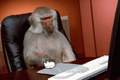 A Monkey Is Sitting At A Desk With A Computer Mouse And Keyboard GIF