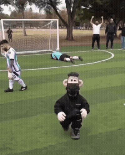 A Monkey Mascot Is Running On A Soccer Field In Front Of A Goalie GIF