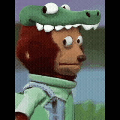 A Monkey Wearing A Green Crocodile Hat Looks At The Camera GIF