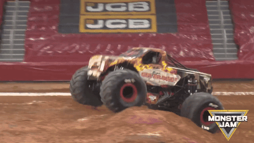 A Monster Jam Truck Is Jumping Over A Dirt Field GIF