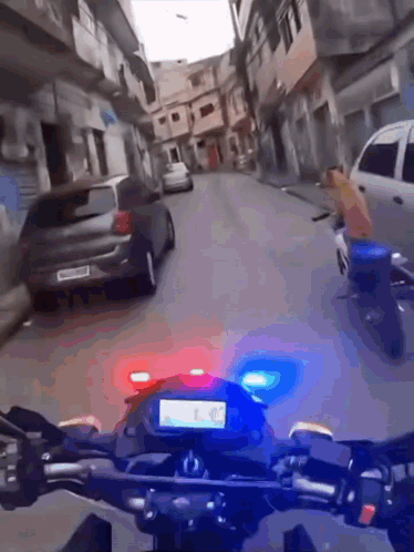 A Motorcycle Is Driving Down A Street With A Car In The Background GIF