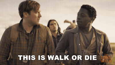 A Movie Poster For The Long Walk Shows Two Men Standing Next To Each Other And Says This Is Walk Or Die GIF