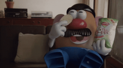A Mr Potato Head Is Sitting On A Couch Eating A Bag Of Saltines GIF