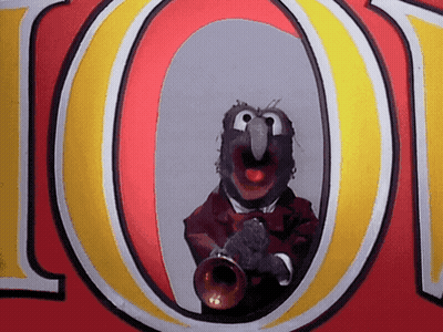 A Muppet Is Playing A Trumpet In Front Of The Letter O. GIF