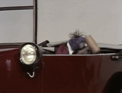 A Muppet Is Sitting In A Red Car With Its Head Out The Window . GIF