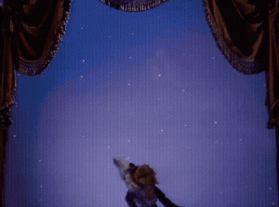 A Muppet Is Standing In Front Of A Stage Curtain GIF