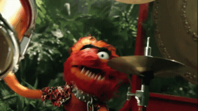 A Muppet Playing A Drum Set With A Jungle Background GIF